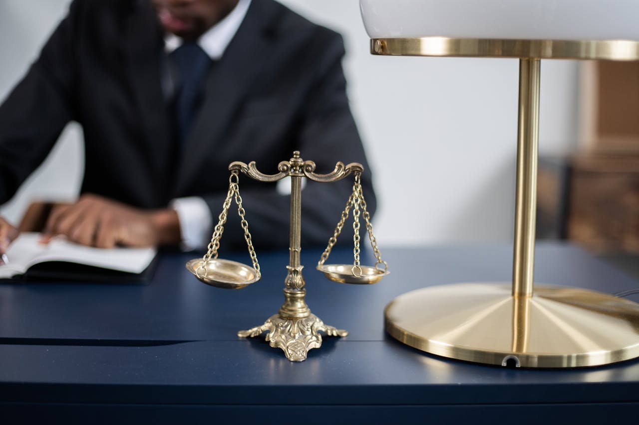 about-img Elegant legal office with a close-up of golden scales of justice on a sleek dark desk.